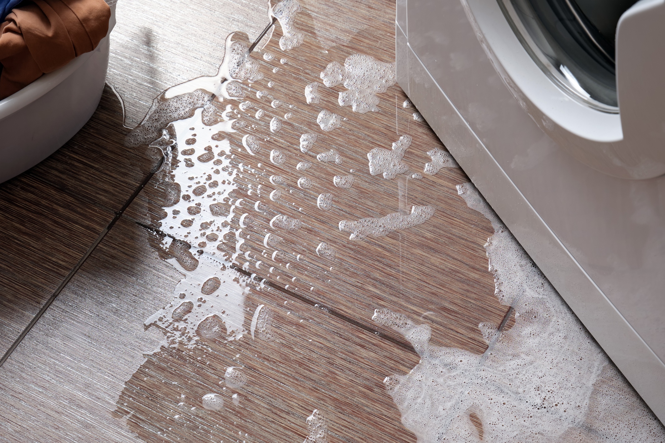 Water with foam on floor from household washing machine