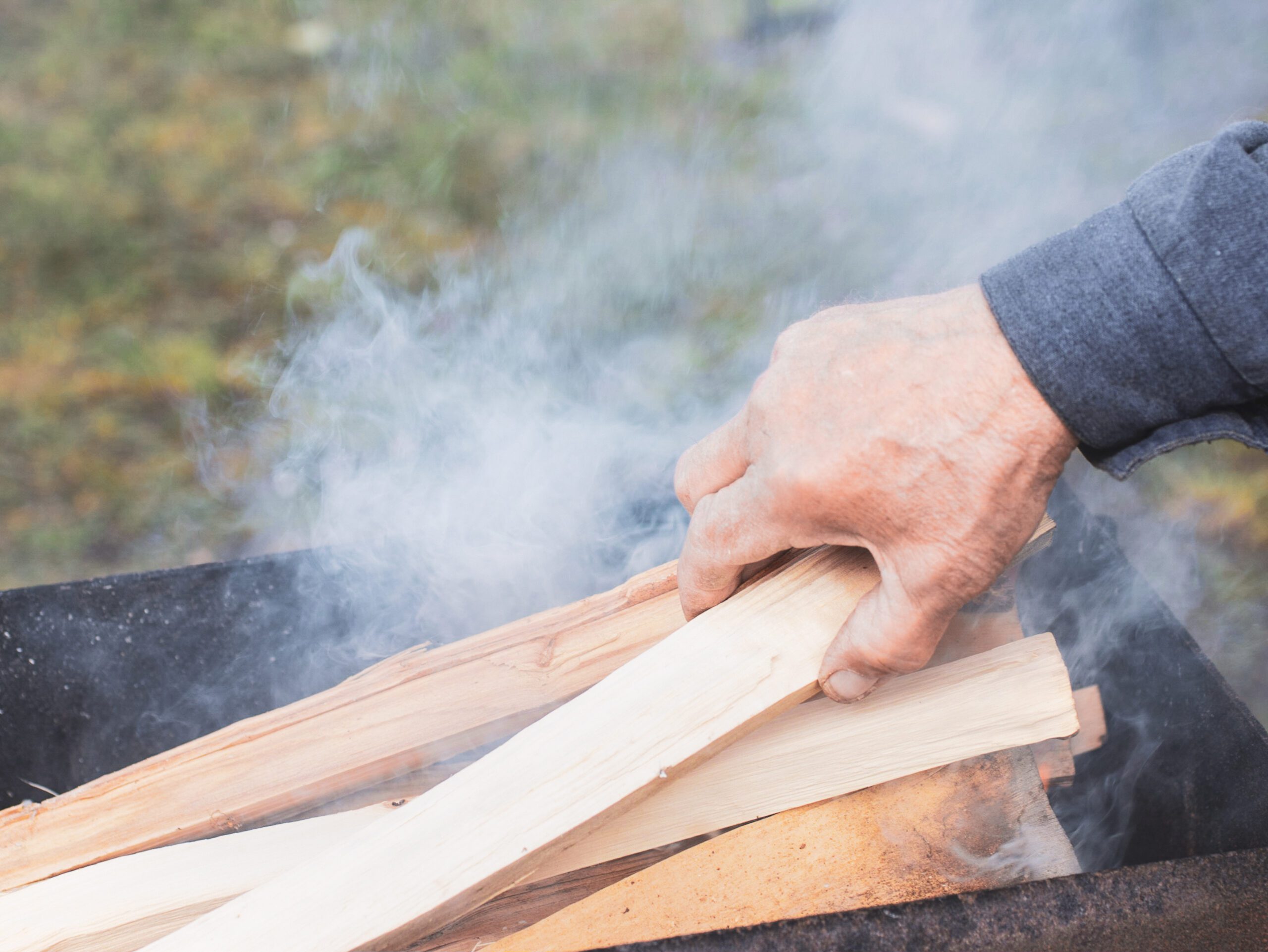 man removing smokey wood with an odor from pile