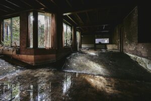 An old, dirty, abandoned building interior. Dirty room with wet floor.