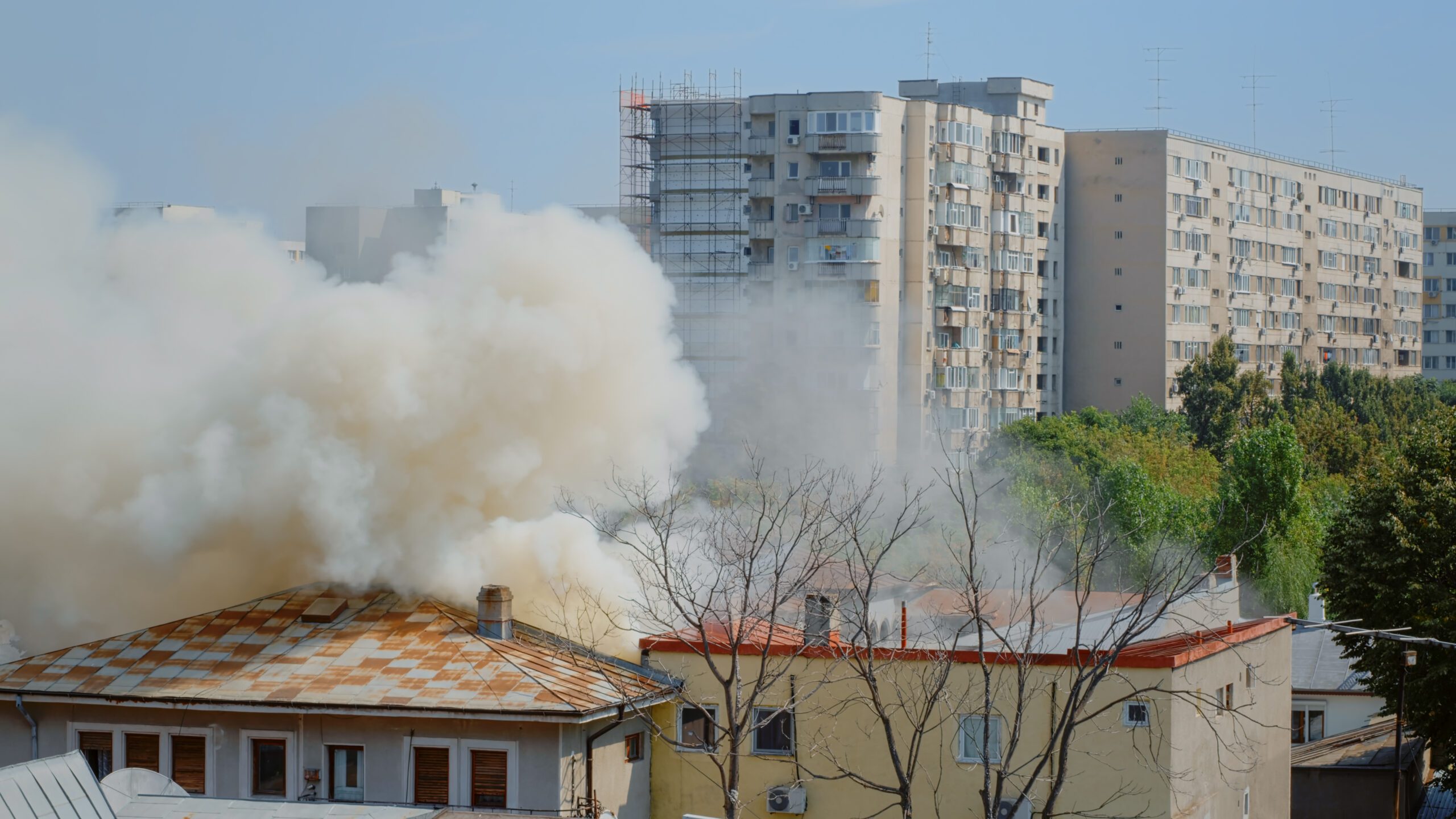 Flames going out from burning house in neighbourhood Flames going out from burning house in neighbourhood. Smoke emerging from roof on fire in city landscape. Dangerous fumes and smog from explosion getting out of destroyed building